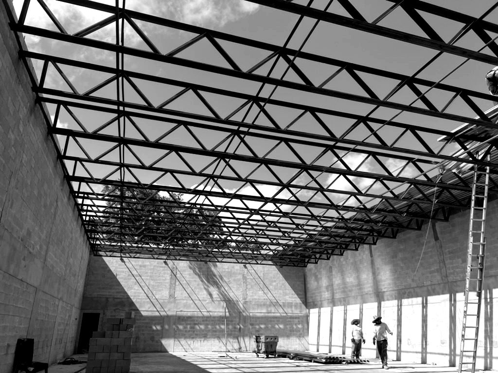 Steel roof trusses spanning concrete block walls, seen from below